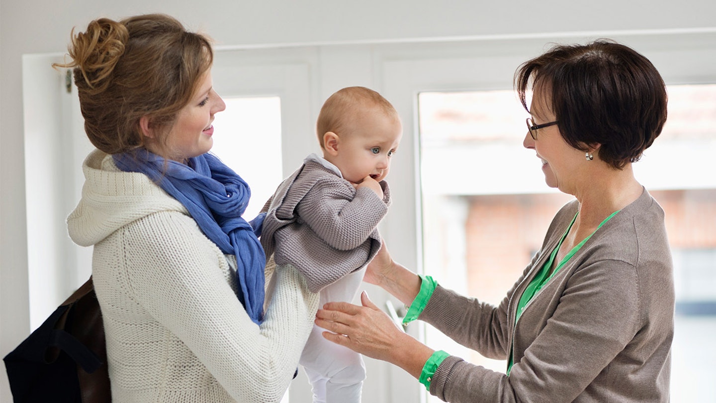 mum handing baby over to babysitter
