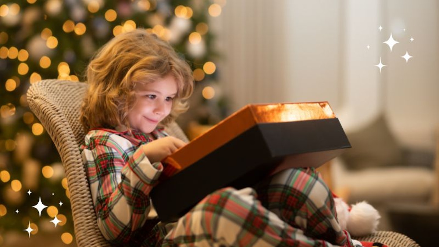 A photo of a child with a Christmas Eve box with sparkles on the corner