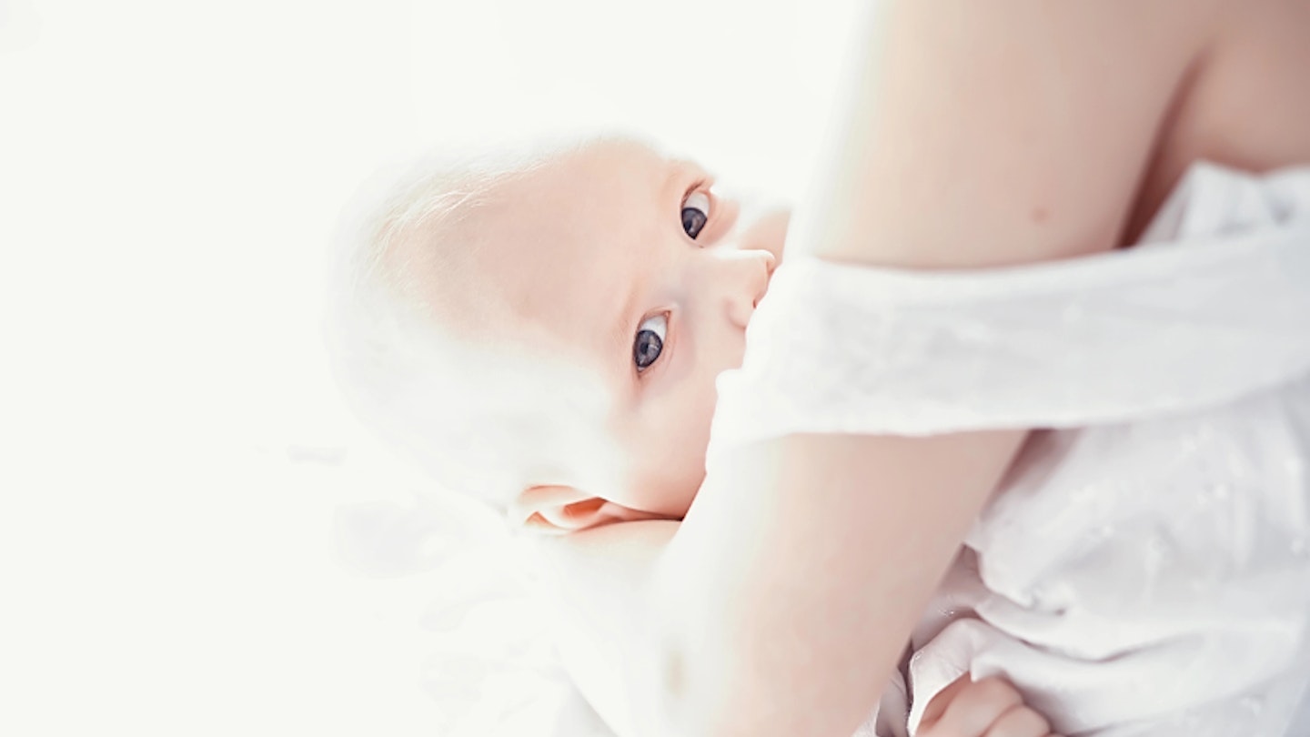 Young mother breastfeeding her toddler baby boy at home