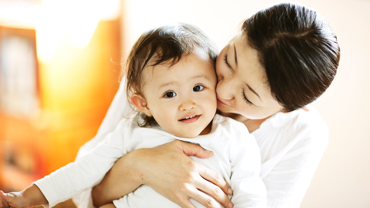 mum holding baby and giving a kiss