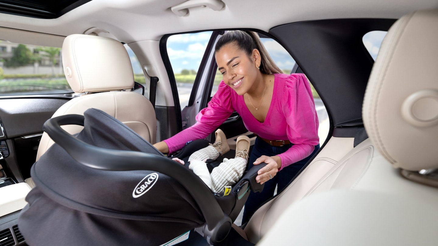 Woman putting child in car seat in car