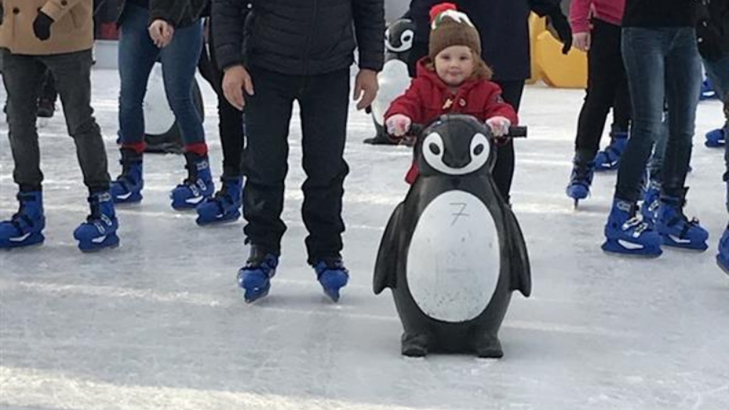 Toddler iceskating with penguin