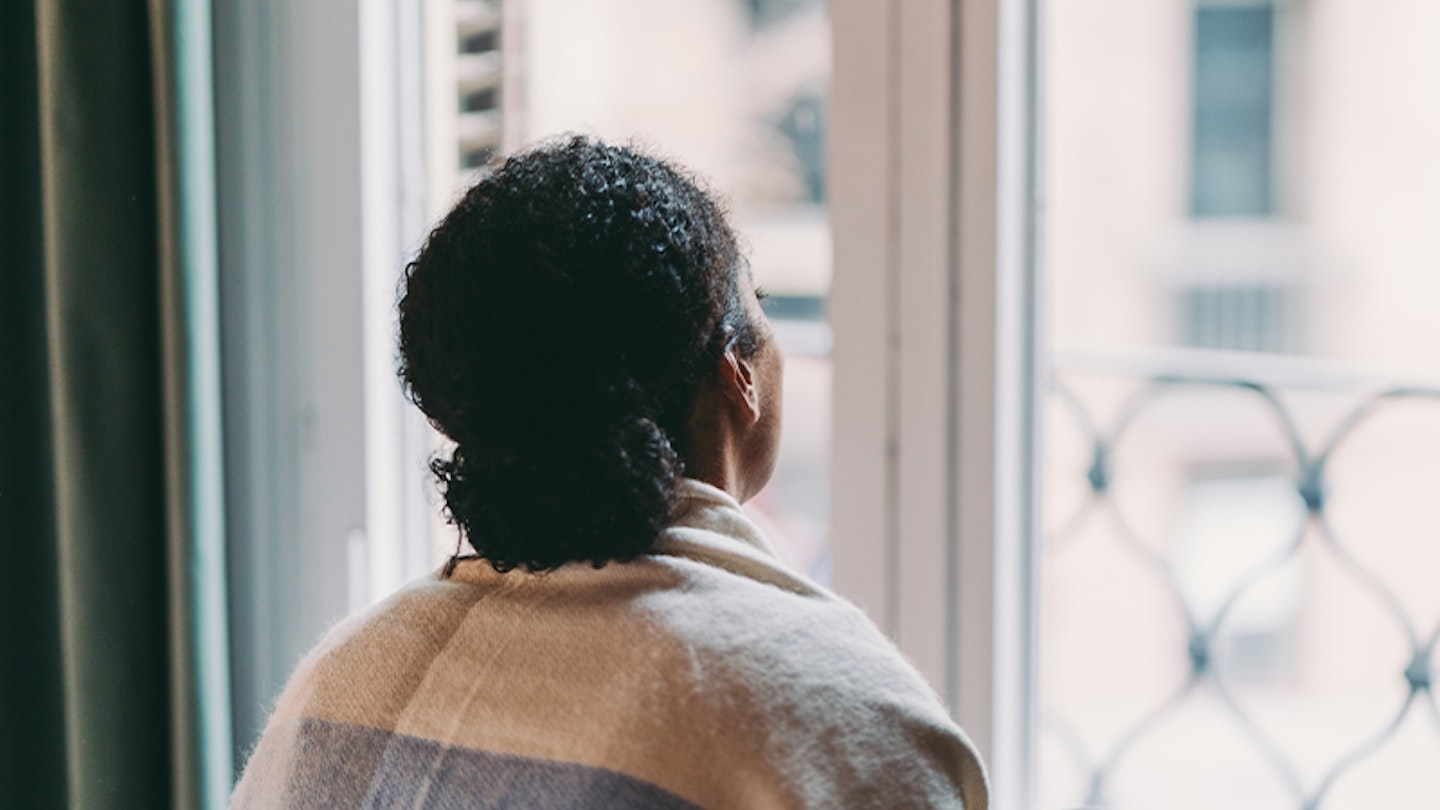 Woman looking out of the window holding a mug