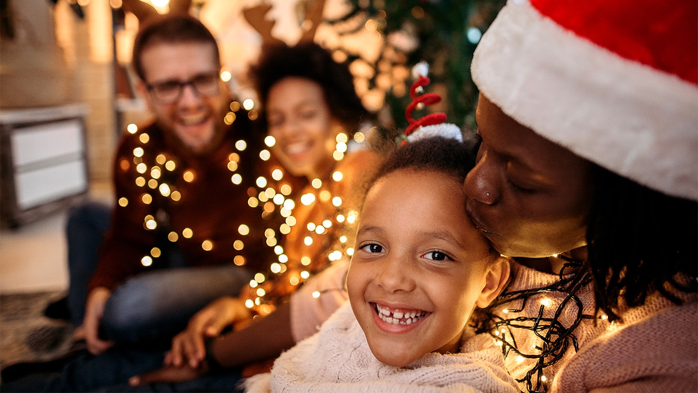 A family surrounded by Christmas lights and wearing father Christmas hats