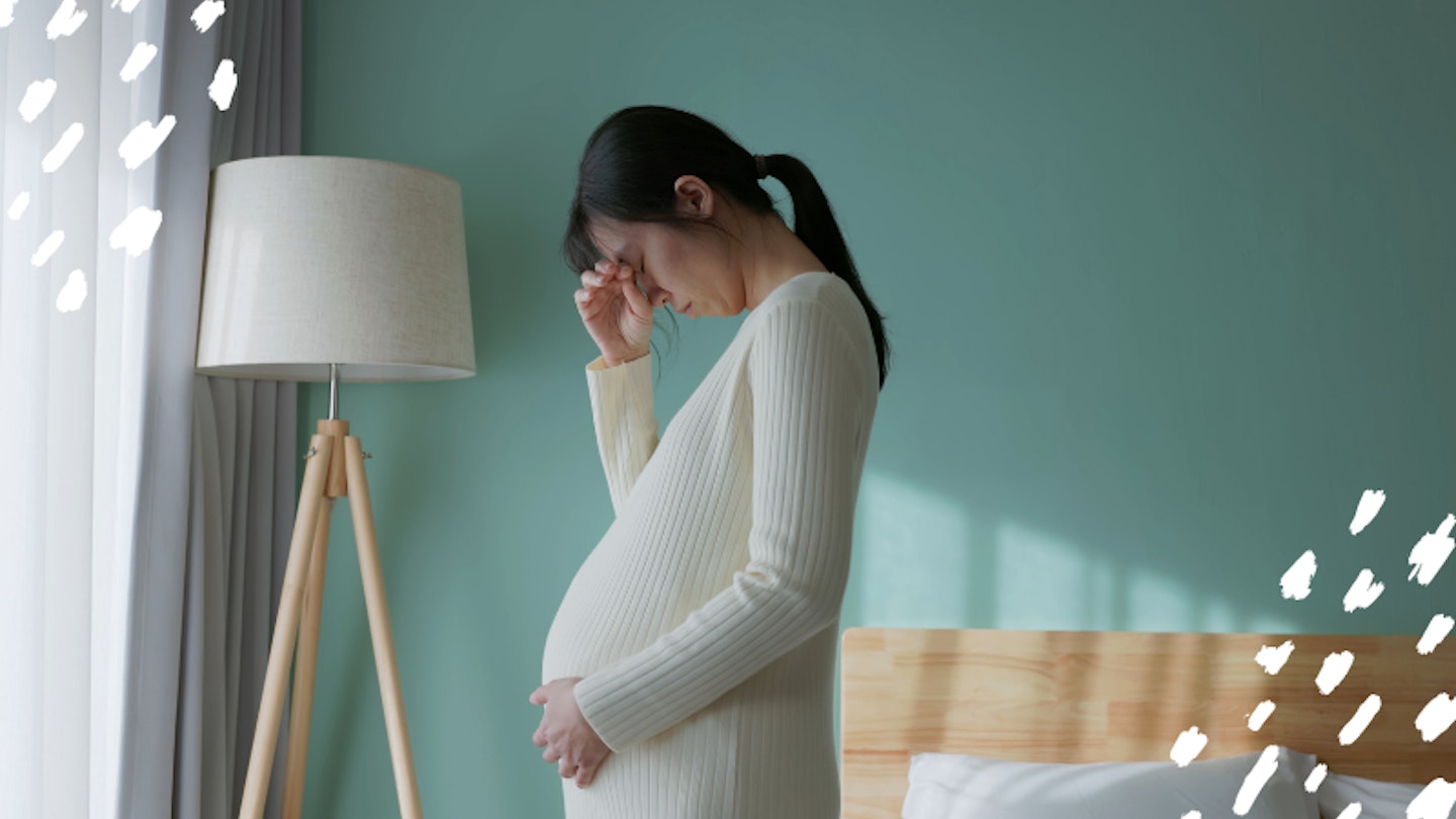 Pregnant woman in bedroom looking sad