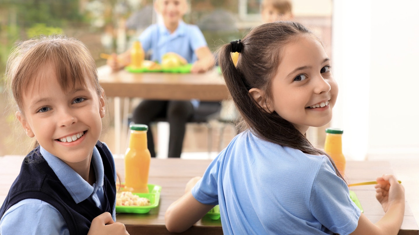 primary school girls eating breakfast in school canteen