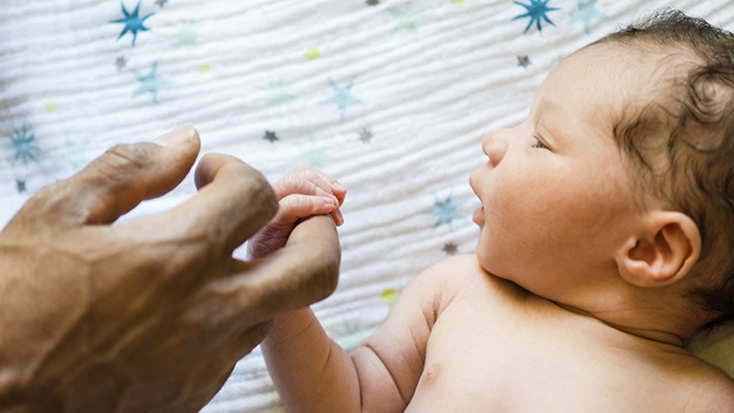 Father holding sleeping baby boys hand