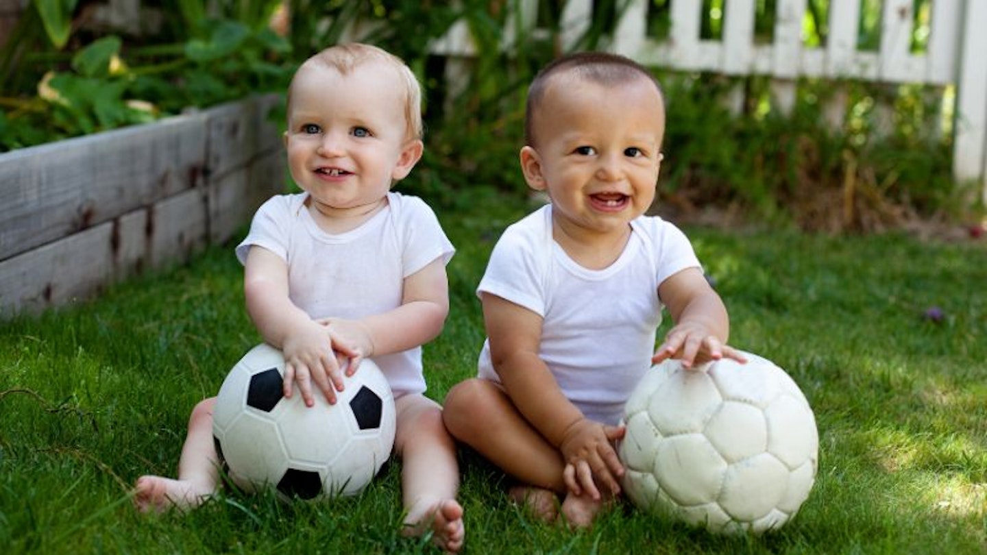 Two babies sitting on the grass with footballs to show athlete baby names