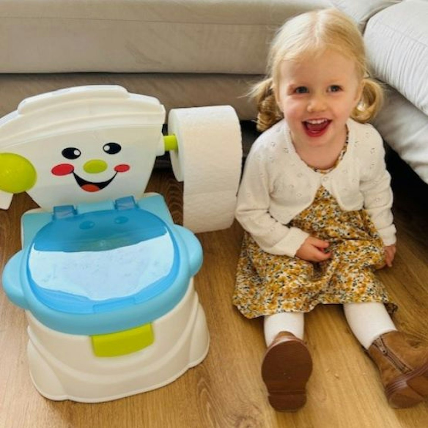 A little girl sitting next to the SA potty looking happy to be testing it out